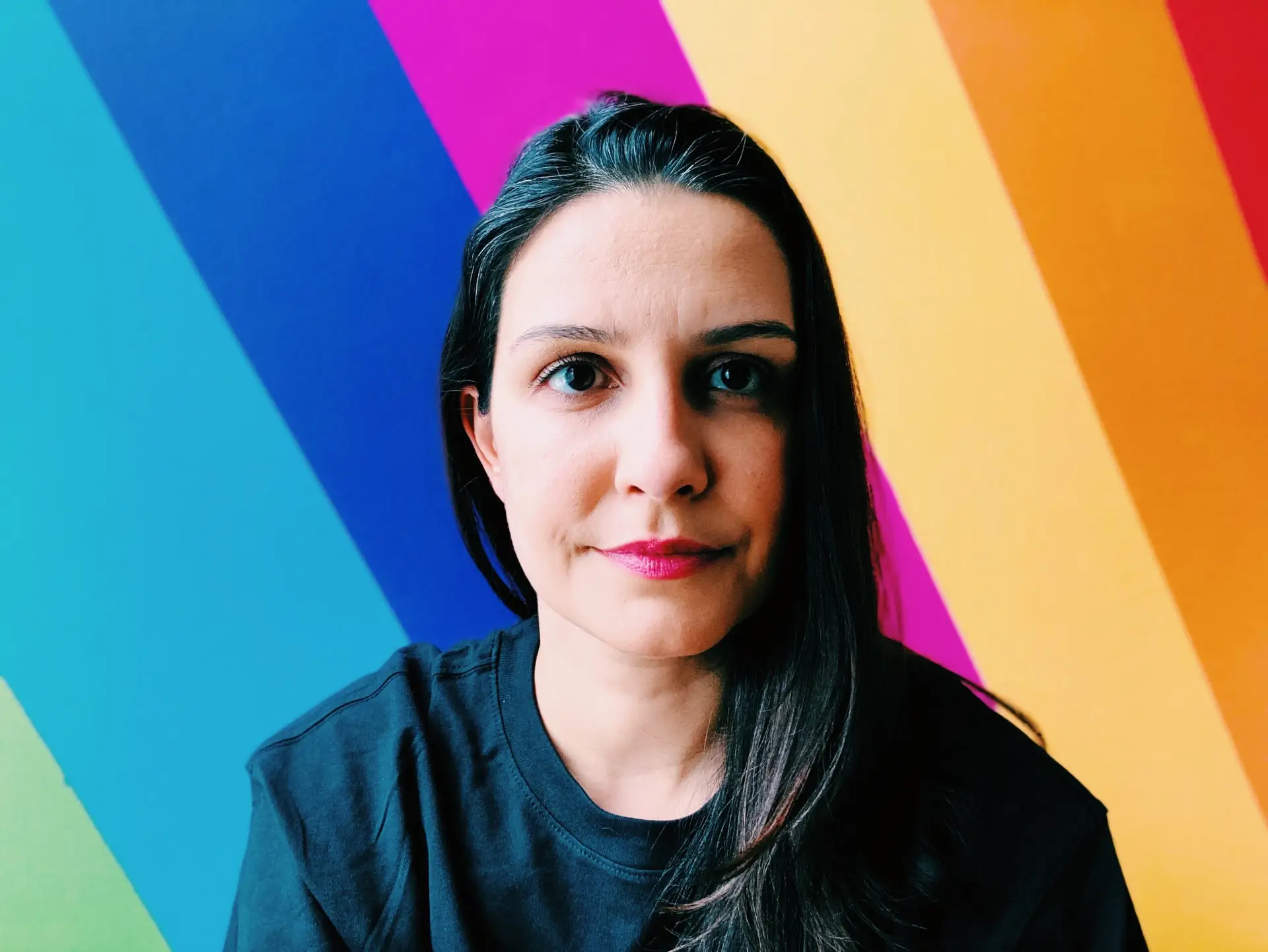 Renata Sene, Toronto-based mural artist, in front of a colourful striped wall