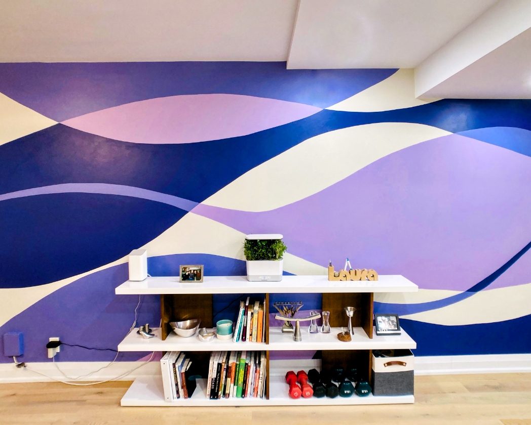 Abstract purple wave mural in home office with flowing shapes in violet, lavender, and indigo behind white shelving