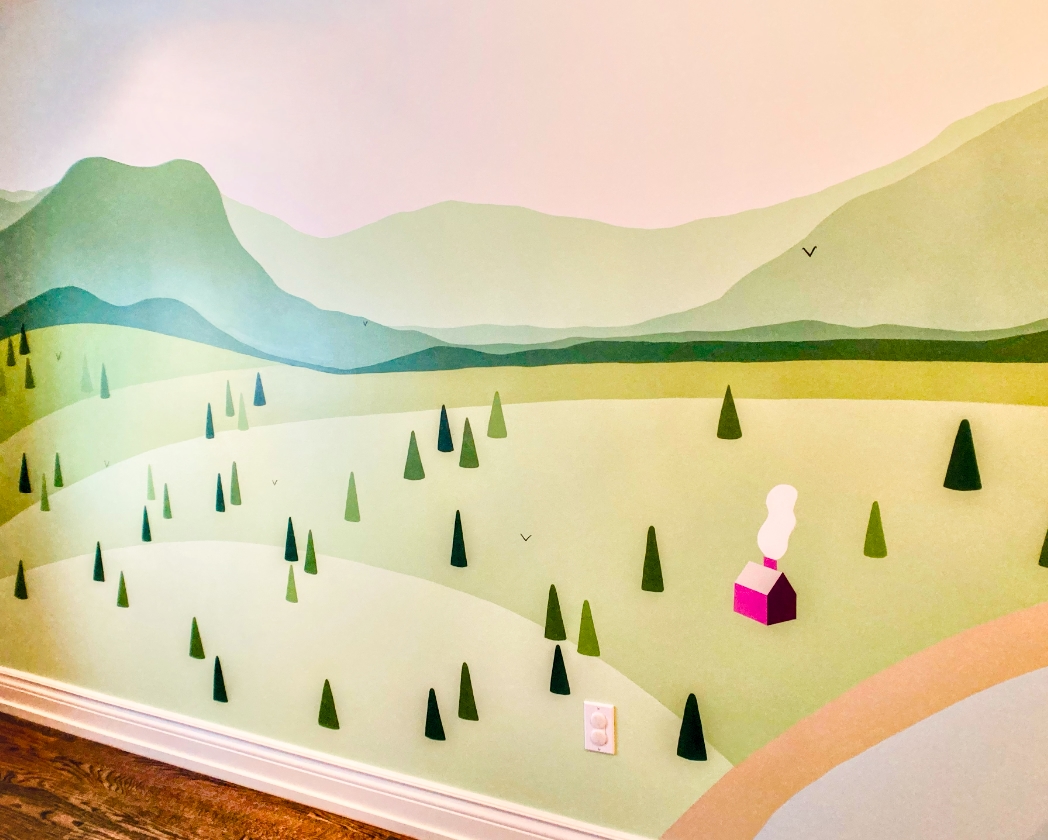 Tofino-inspired forest mural close-up with layered green mountains, scattered pine trees in varied shades, and small pink cabin with chimney smoke