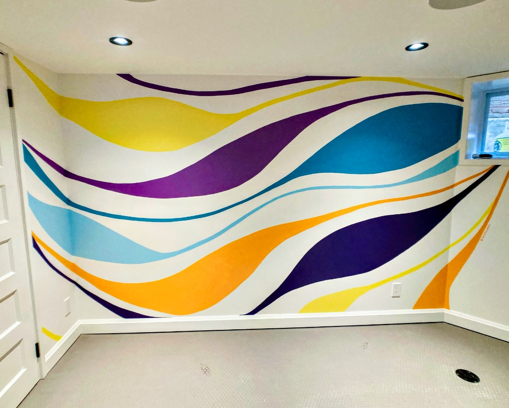 Vibrant flowing waves abstract mural with ribbons of purple, yellow, teal, and orange in a basement room